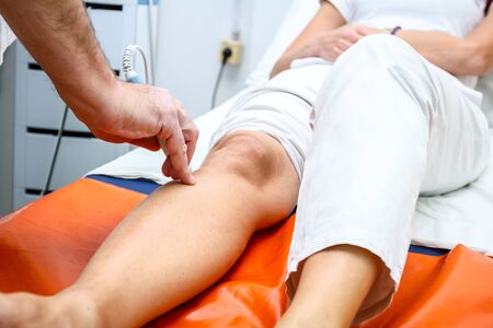 Physical therapist is treating patient knee with magnet therapy.