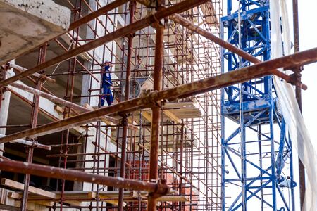 Scaffold with wooden platform is placed against edifice, building under construction.