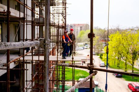 Scaffold is placed against edifice. Boss is oversees from platform above building site.