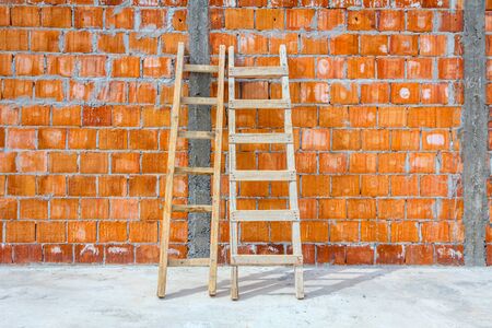Front view on used wooden ladders, leaning against the wall for access, reaching to higher place at...