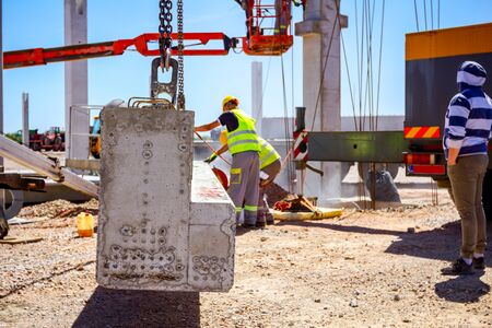 Worker is using abrasive grinding machine to set up concrete joist to right length until it hang on...