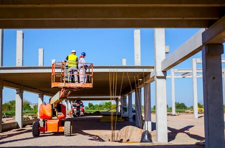 Rigger is in high elevated cherry picker, he is moving over construction site.