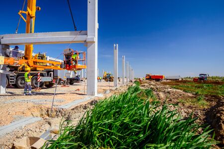 Workers are helping mobile crane to manage concrete joist for assembly huge construction.