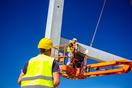 View from behind on construction worker with safety vest and yellow helmet.の写真素材