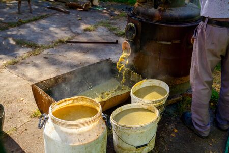 Man is unloading boiler of homemade distillery made of copper to release used fruit marc, making...