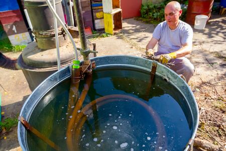 Condenser made of twisted copper pipe bent in helical shape submerged in cold water for cooling...