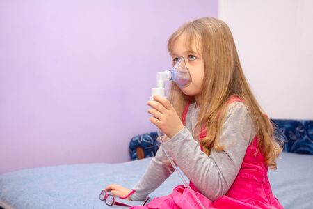 Child with asthmatic problems is take inhalation with mask on her face, home therapy.の写真素材