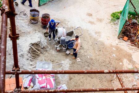 Above view on construction site area, construction worker is making concrete in the mixer.