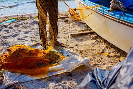 Fisherman is taking out fish from net and prepare for his next angling. の写真素材