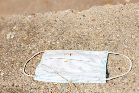 Used protective medical mask dumping on the city ground. Coronavirus, Covid-19 and Environmental...
