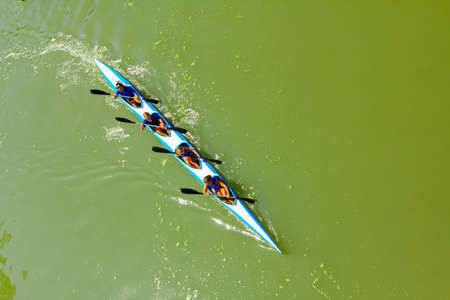 Above view on young rowers who have a competition in rowing kayaks on the river.