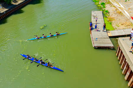 Young rowers have a competition in kayaking on the river, children sit on the wooden planks and...