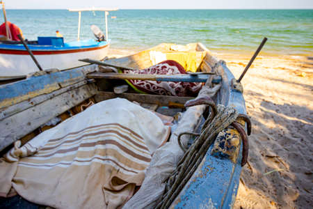 Docked fishing boat on the sandy beach is full of fishing equipment, fishnet.