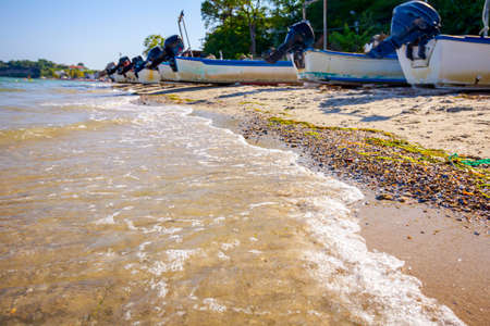 View on the calm sea and pebbly sandy beach, fishing boats are dry docked.