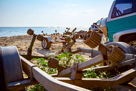 Several cars are parked on the beach with trailers for transport boats.