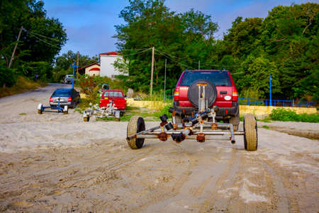 Several cars are parked on the beach with trailers for transport boats.
