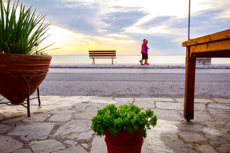 Flowerpots with flowers are placed on a paved promenade above public beach in the early morning.