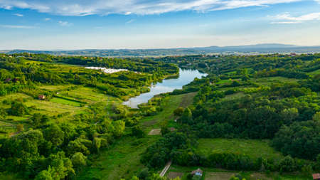 Aerial view over lake next to the colorful forest on hilly landscape, treetops