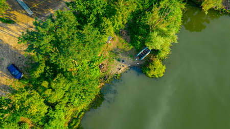 Fishing place on shore of lake, river, in green landscape, dinghy boat is placed out of water.の写真素材