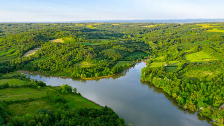 Aerial view over lake next to the colorful forest on hilly landscape, treetops