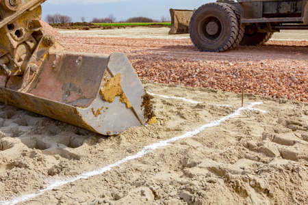 Excavator will excavate square trench that is marked with white powder lime at construction site, project in progress.の写真素材