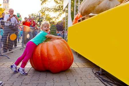 Kikinda, Vojvodina, Serbia - October 11, 2014: Cute little child hugs a giant, massive pumpkin displayed on stage at traditional holiday competition.のeditorial素材