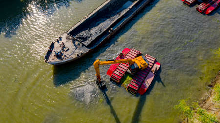 Above top view on excavator dredge is dredging, working on river, canal, deepening and removing sediment, mud from riverbed in a polluted waterway.の写真素材
