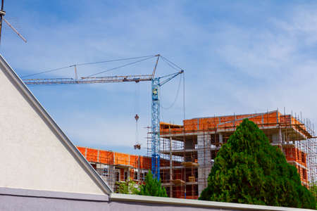 Scaffold and crane are placed against unfinished edifice, building under construction.