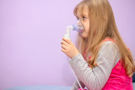 Child with asthmatic problems is take inhalation with mask on her face, home therapy.の写真素材