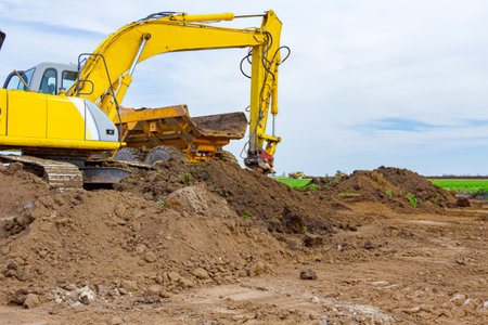 Big excavator is filling a dumper truck with soil at construction site, project in progress.のeditorial素材