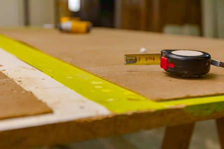 Measuring tape for measurement is placed on the plywood in carpentry workshop.の写真素材