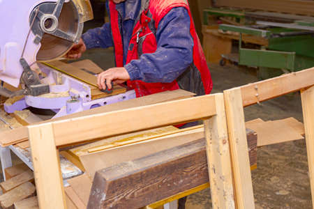 Carpenter has cut the planks on the manual circular saw and checks the length using a measuring tape...