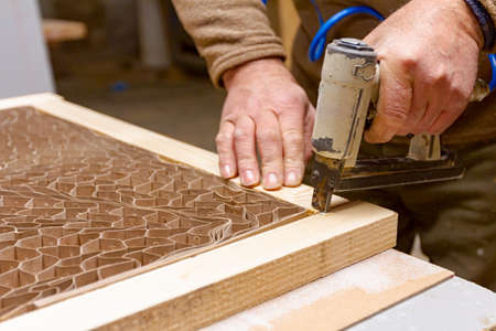 Carpenter puts together planks on the door frame using a pneumatic stapler in the carpentry...