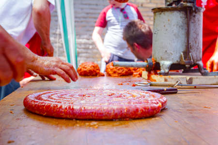 Butcher twists fresh intestine filled with minced meat, divide to make sausages approximately same length.の写真素材