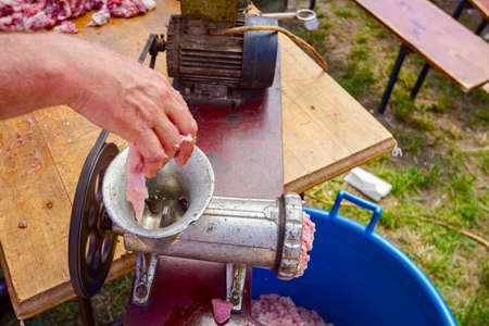 Above view on meat grinder machine, forcemeat process for making sausages at outdoor kitchen.