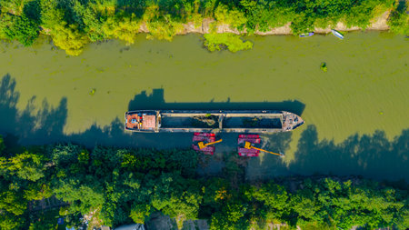 Above top view on two excavators dredge as they dredging, working on river, canal, deepening and...