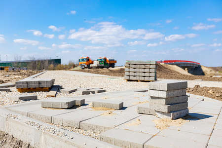 Bricklayer placed grey concrete paving stone blocks for building sidewalk path.