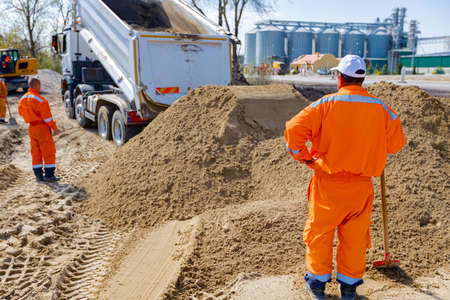 Workers are waiting for dumper truck to unloading soil or sand at construction site.の写真素材