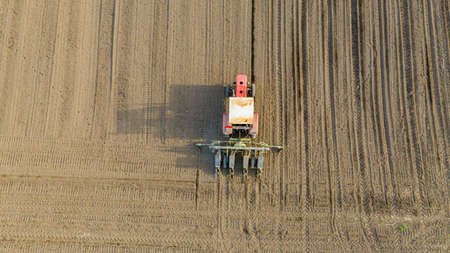 Above top view, of tractor as pulling mechanical seeder machine over arable field, soil, planting...