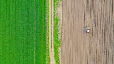 Above top view, of tractor as pulling mechanical seeder machine over arable field, soil, planting...
