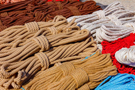 Close up shot of heap of braided hemp ropes made for sale at outdoor flea market. Manila ropes