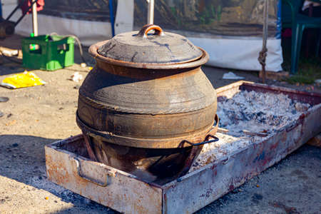 Big amount of food is cooking in a large ceramic, clay pots on embers.の写真素材