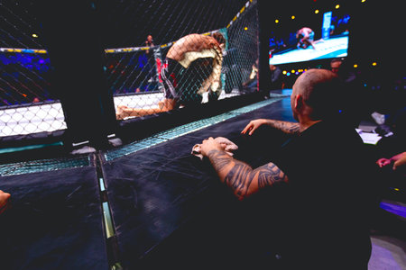 Tattooed hand of trainer with towel in it, he is rooting for the fighters, they are fighting in ring parterre on octagon floor.のeditorial素材