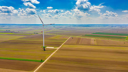 Above view on farm of large wind power turbines are standing among agricultural fields, generating clean renewable electrical energy for sustainable development.の写真素材