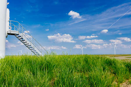 Entrance, doorway with stairs into large wind power turbine at farm for generating clean renewable electrical energy producing renewable clean energy by converting kinetic energy.の写真素材