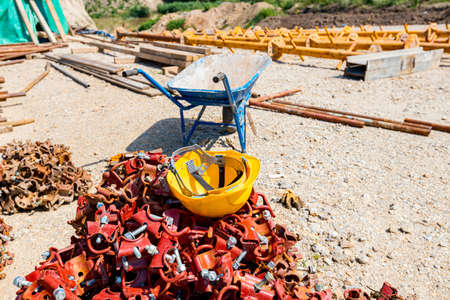 Yellow safety helmet placed on the heap of disassembled steel scaffolding joint on construction site.の写真素材