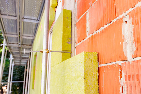 Applying thermal isolation stone wool on the brick wall of residential building under construction. Heat insulation with mineral wool.の写真素材