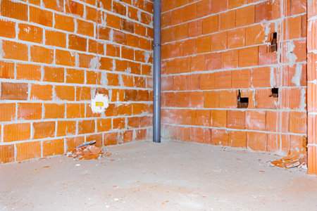 New grey mounted sewerage pipe passing between floors in the residential building under construction. Distribution box with wire was installed in the wall.の写真素材