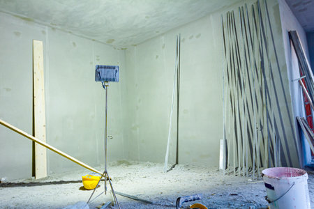 Switched on reflector casts light on the unfinished walls of residential building under construction, ladders and various tools are placed for easier renovation.の写真素材