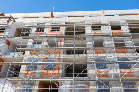 View from below on scaffold placed against unfinished edifice, new residential building under...